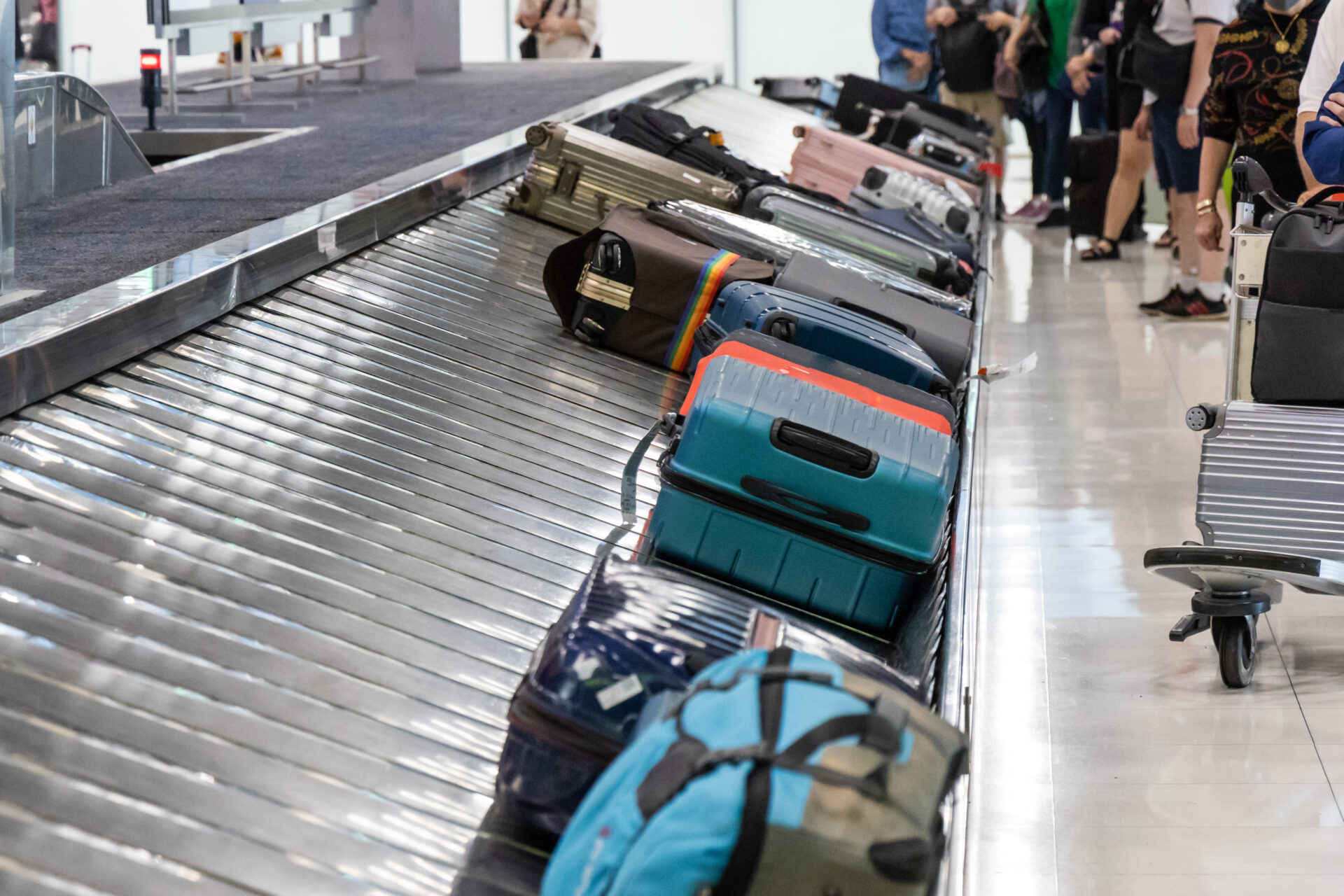 Baggage luggage at airport arrival carousel with passengers awiating to claim theirs